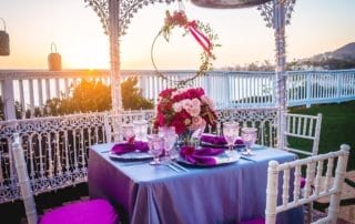 A table set up with purple and pink tablecloths and candles at a Laguna Beach wedding venue.