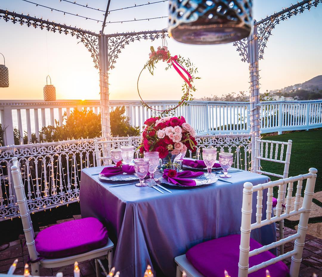 A table set up with purple and pink tablecloths and candles at a Laguna Beach wedding venue.