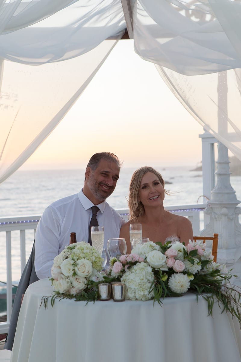 A couple celebrating their special day at a table overlooking the ocean at one of the stunning wedding venues in Southern California.