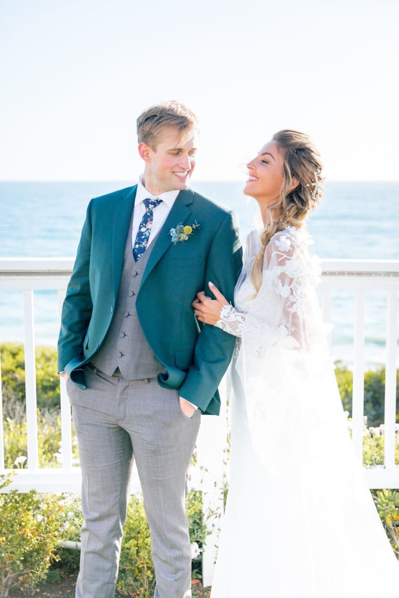 A bride and groom standing on a porch overlooking the ocean at one of the stunning Laguna Beach wedding venues in Southern California.