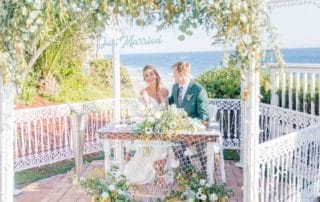 A bride and groom enjoying their special day at a table by the stunning ocean views of Laguna Beach, one of the finest Southern California wedding venues.