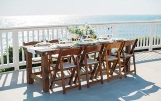 A wooden table set on a deck overlooking the ocean at one of the picturesque Laguna Beach wedding venues in Southern California.