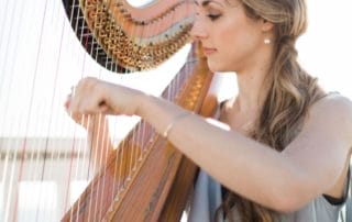 A young woman playing a harp on a deck, creating an enchanting ambiance for a Southern California wedding.