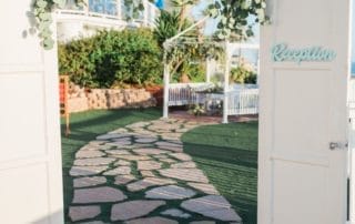 A white door with a pathway leading to a beach wedding at one of the best southern CA wedding venues.