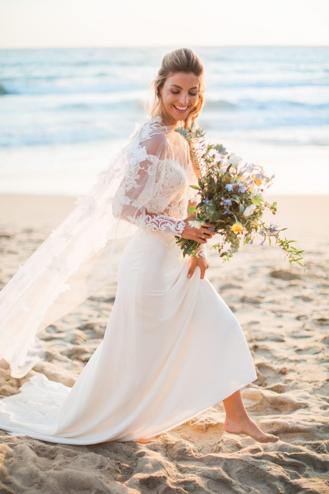 A bride walking on the beach holding her wedding bouquet at a picturesque wedding venue in Laguna Beach, Southern California.