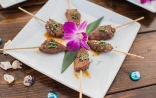 A plate of meat skewers on a wooden table at a wedding venues in Southern California.