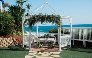 A picturesque white gazebo set up in front of the mesmerizing ocean serving as a dreamy wedding venue in Southern California.