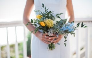 A bride holding a bouquet of yellow and blue flowers at one of the stunning wedding venues in Laguna Beach, Southern California.