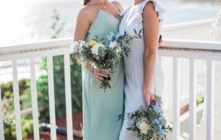Two bridesmaids posing for a photo on a balcony overlooking the ocean in one of the stunning wedding venues in Laguna Beach.
