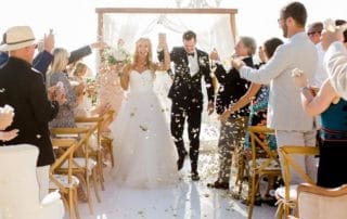 A bride and groom walking down the aisle with confetti thrown at them in one of the exquisite wedding venues in Southern California.